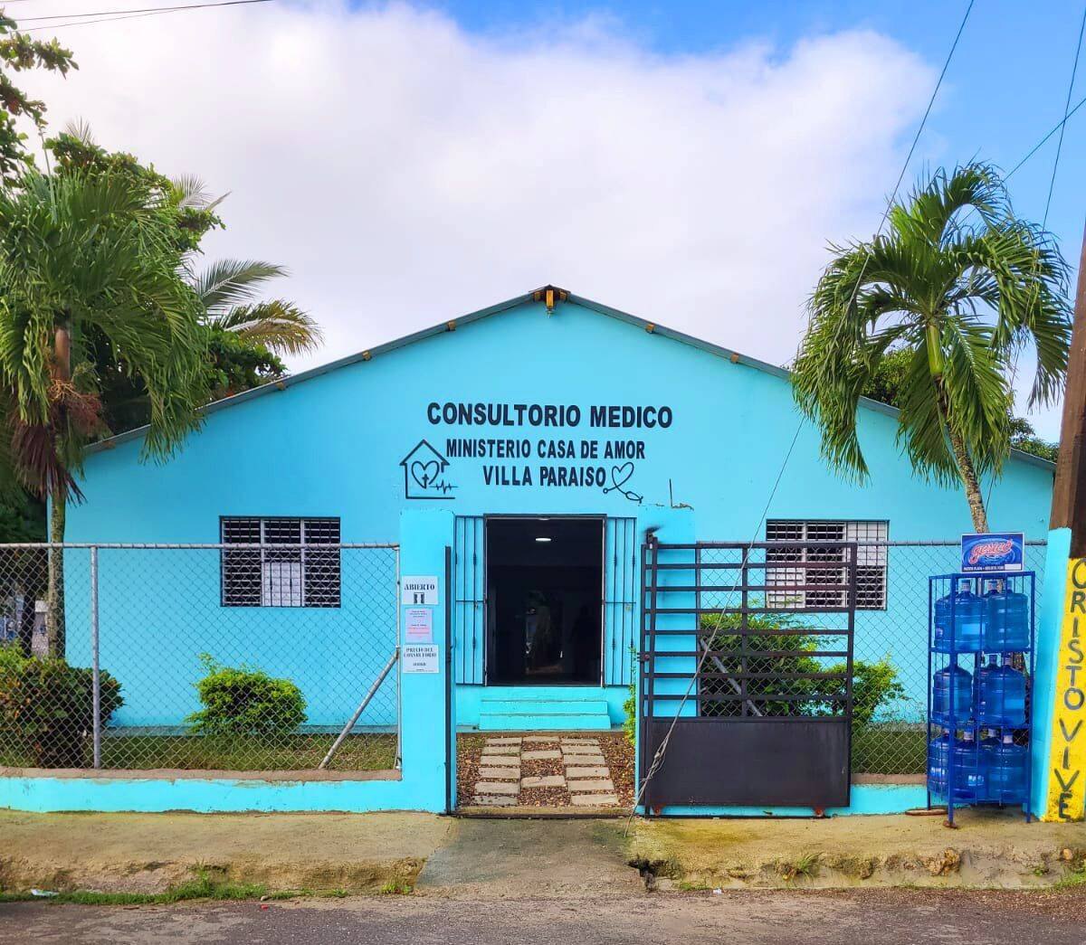 The Casa De Amor medical clinic in Villa Paraiso, a bright teal building painted with the words Consultorio Medico, Ministerio Casa de Amor, Villa Paraiso.
